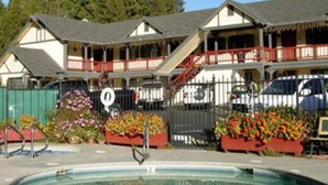 A hotel with a pool, outdoor seating, and a covered porch area. - Wildwood Inn (Twain Harte)