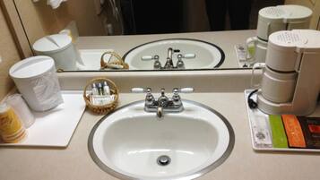 Une salle de bain d’hôtel équipée d’un lavabo, d’un miroir, d’articles de toilette et d’une machine à café.
