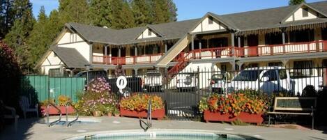 A hotel with a pool area, outdoor seating, and a fenced garden.