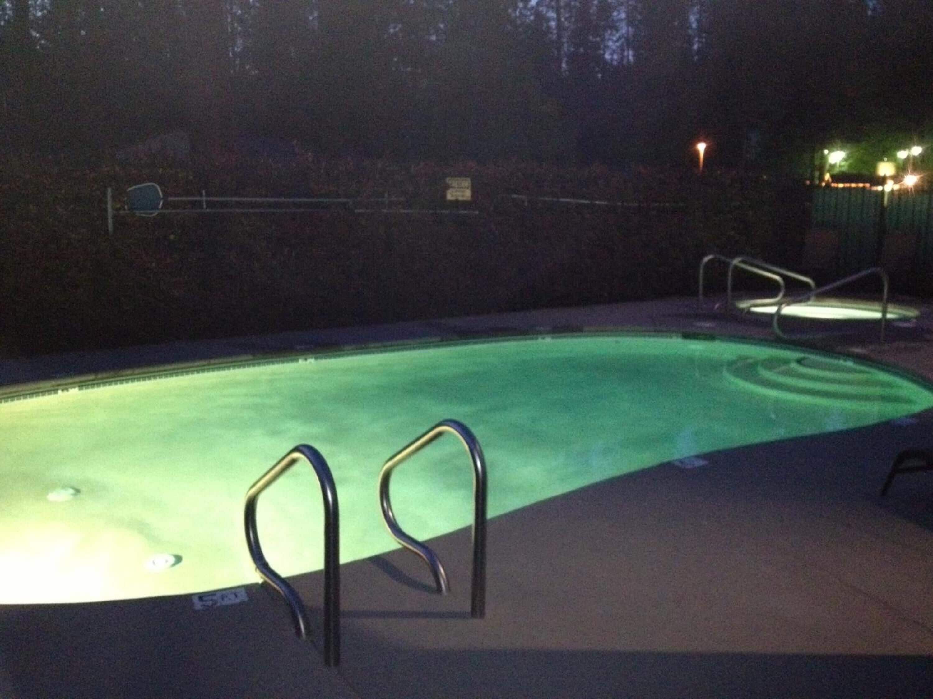 Une piscine avec des échelles en métal et une terrasse carrelée.