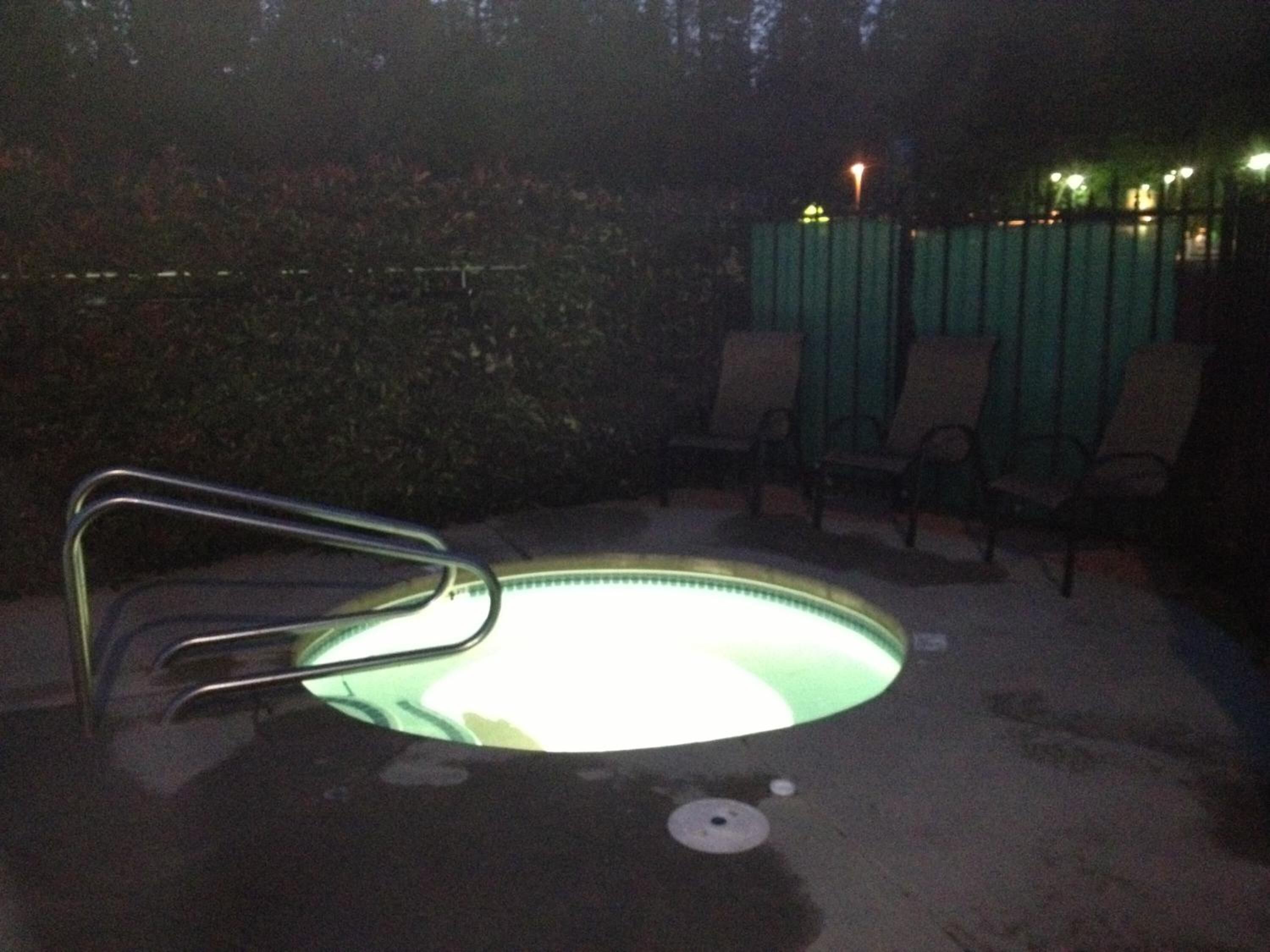 Une piscine avec une chaise en métal au premier plan.