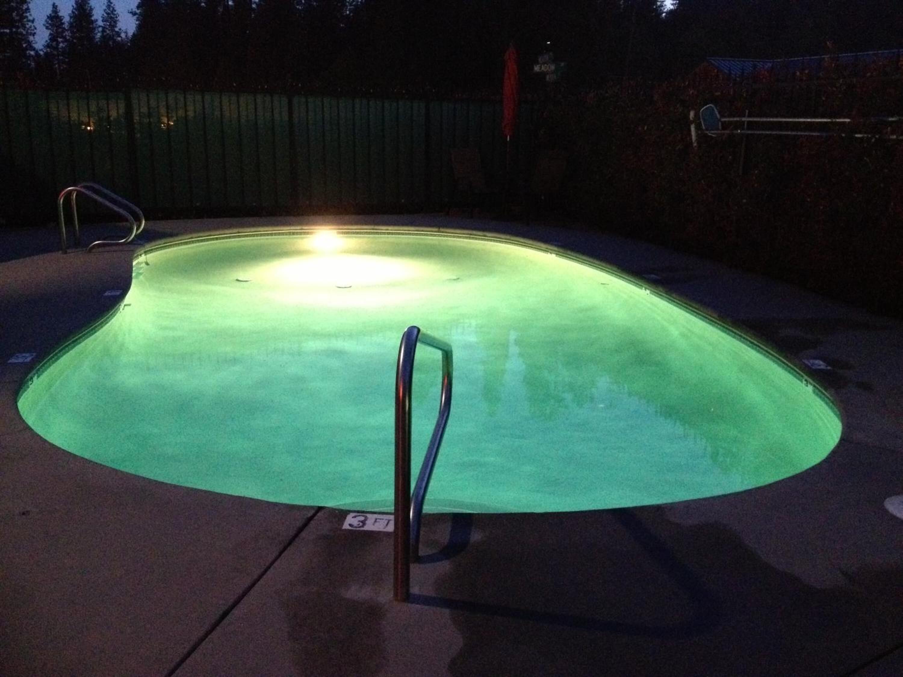 A swimming pool with a curved edge, a metal handrail, and a sign indicating a depth of 3 feet.