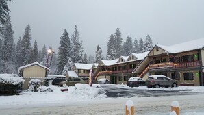 A snow-covered lodge with multiple levels and balconies, surrounded by snow-covered trees. - Wildwood Inn (Twain Harte)