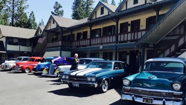 A motel with a row of classic cars parked in front. - Wildwood Inn (Twain Harte)
