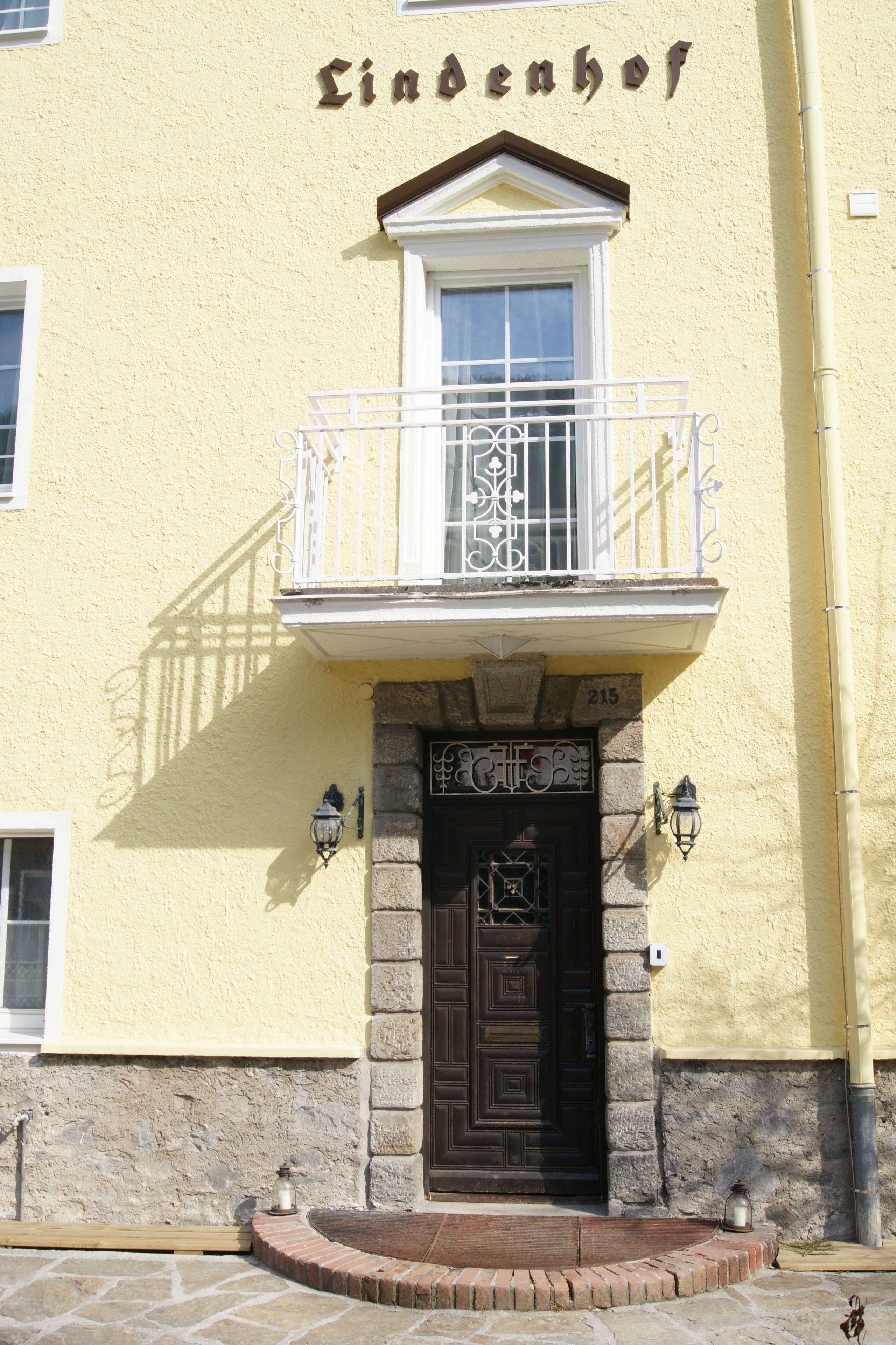 A building with a yellow facade, a black door, and a balcony with a white railing.