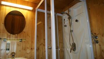 A wooden interior with a glass-enclosed shower, a sink, and a mirror.