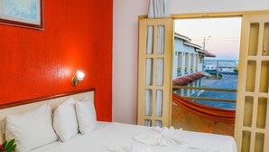 A hotel room with a bed, white pillows, and towels arranged on the bed. - Garça Branca Praia Hotel (Porto Seguro)
