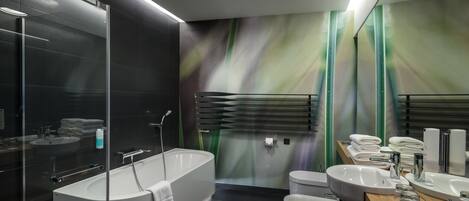 A modern bathroom with a freestanding bathtub, a vanity with multiple sinks, and a large mirror.