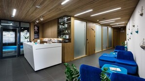 A reception area with a wooden ceiling, a reception desk, blue seating, and a glass display case. - Regatta Hotel Restauracja Spa (Poznan)