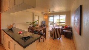 Amplia sala de estar con mesa de comedor, sillas, sofá y televisor. Balcón con vistas al exterior.