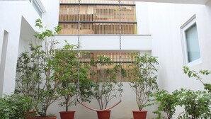 Un patio con plantas en macetas y un sillón colgante.