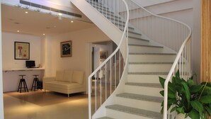 Un interior moderno con una escalera espiral, un sofá y una planta en maceta.