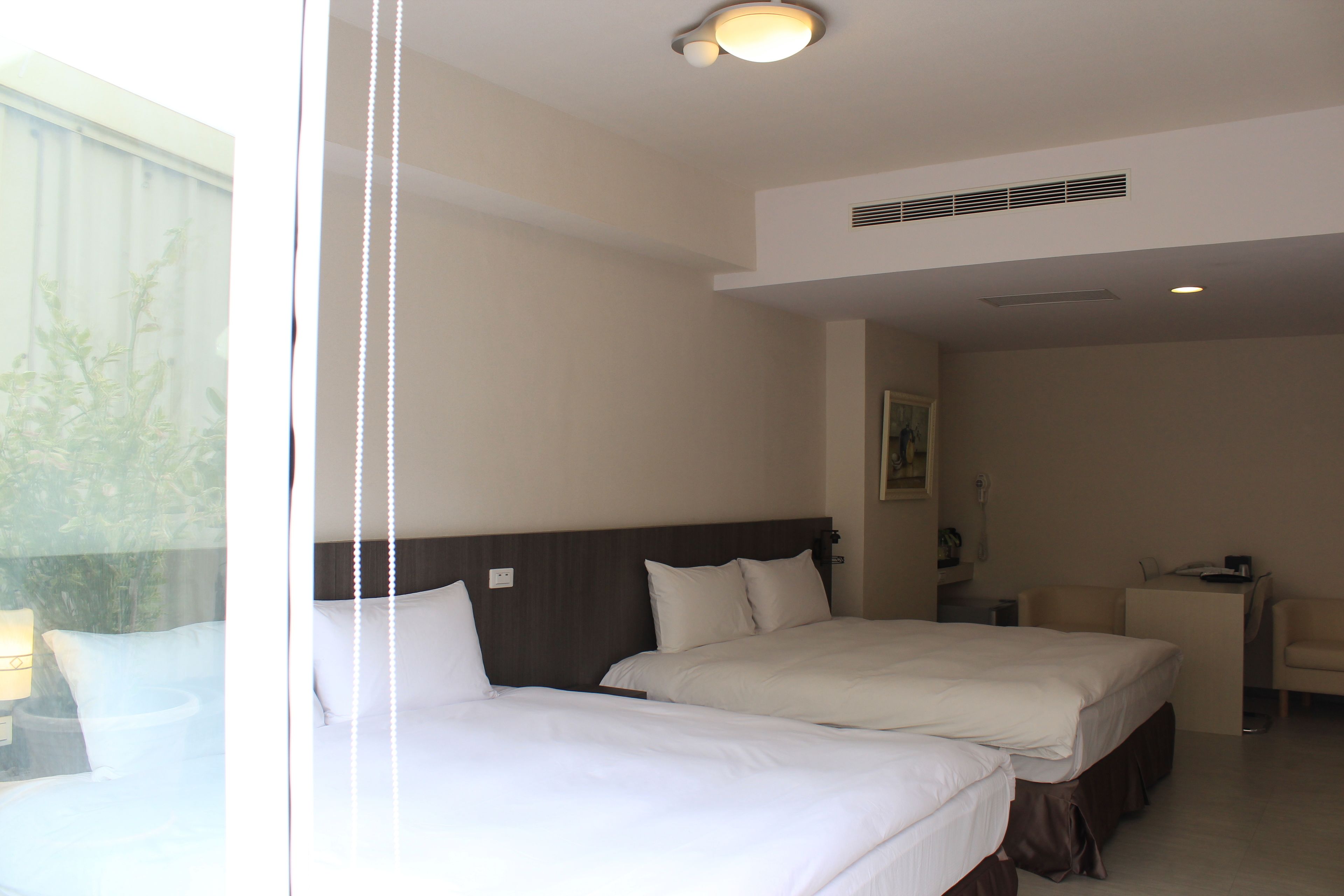 A hotel room with two beds, a desk, and a chair.