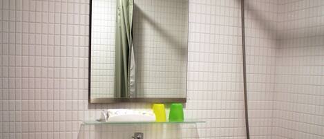 Un baño con inodoro, lavabo, espejo y ducha.