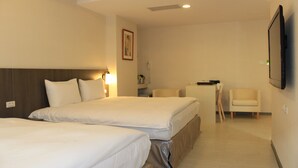Habitación de hotel con dos camas, un escritorio, una silla, un televisor y un cuadro en la pared.