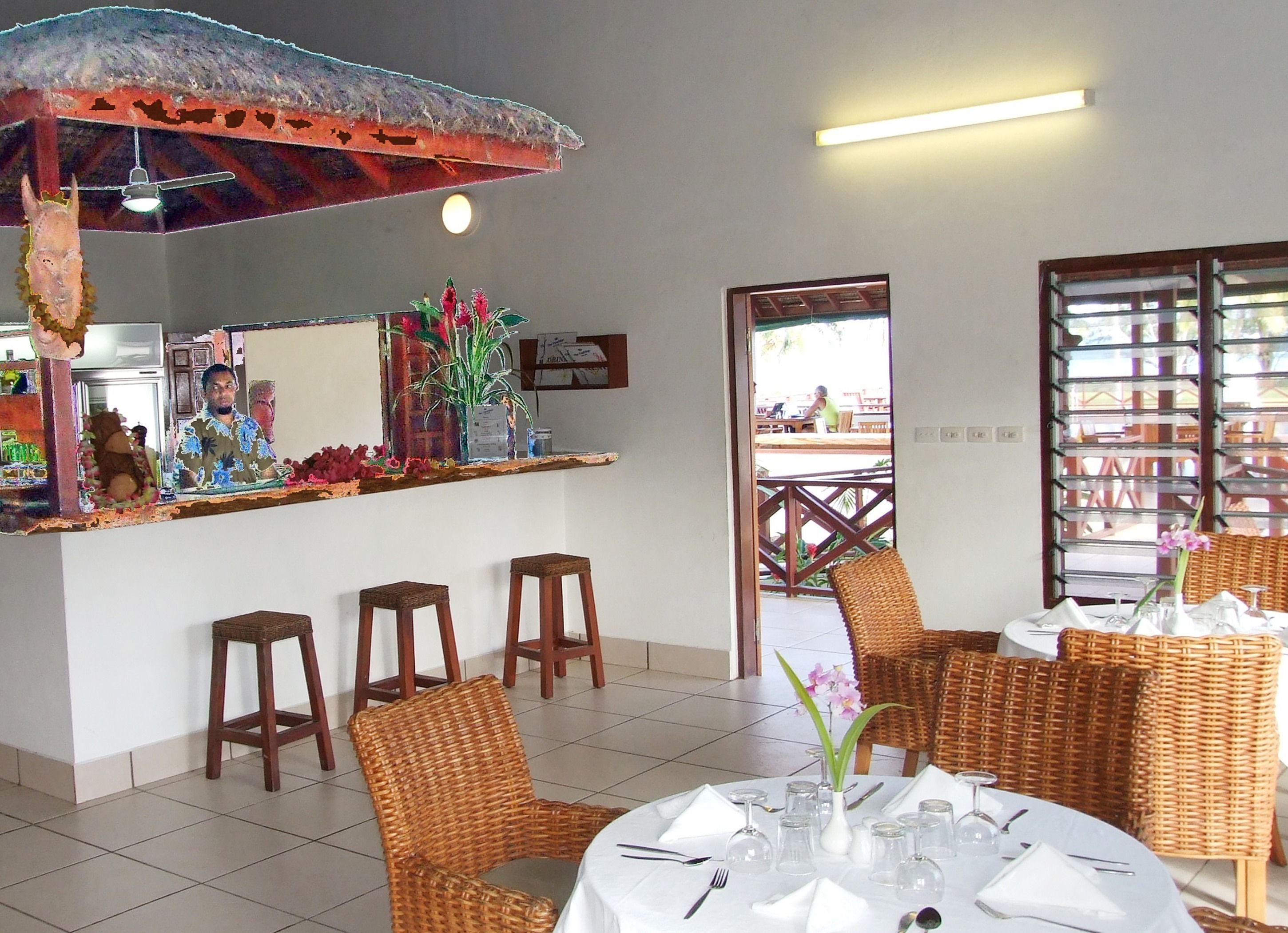 A restaurant with wicker chairs, a bar area, and a view of the outside.