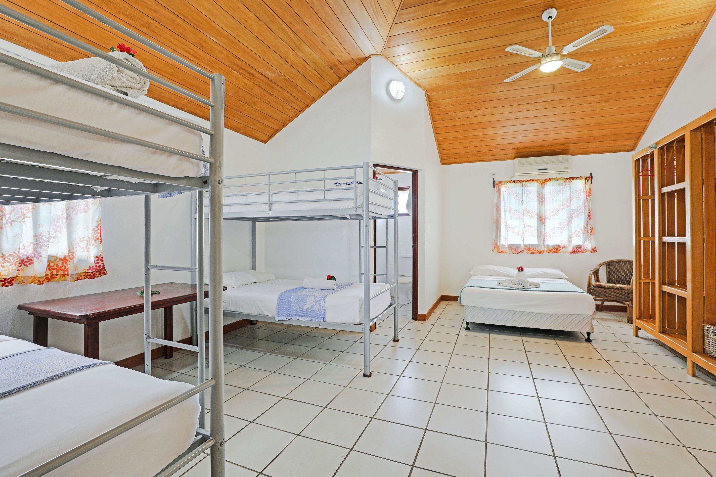 Une chambre de dortoir avec des lits superposés, un bureau, une chaise et une armoire.