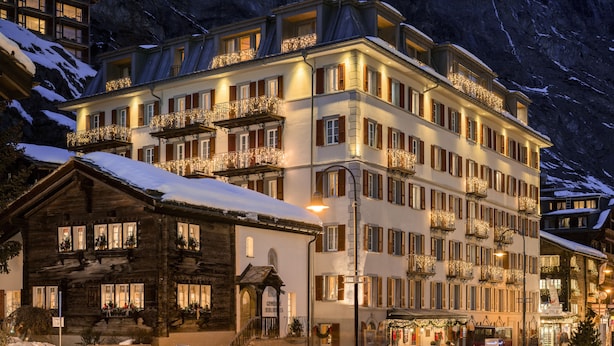 A multi-story hotel with balconies, a snow-covered roof, and a sign that reads "GOLDEN BELL". - Hotel Monte Rosa (Zermatt)