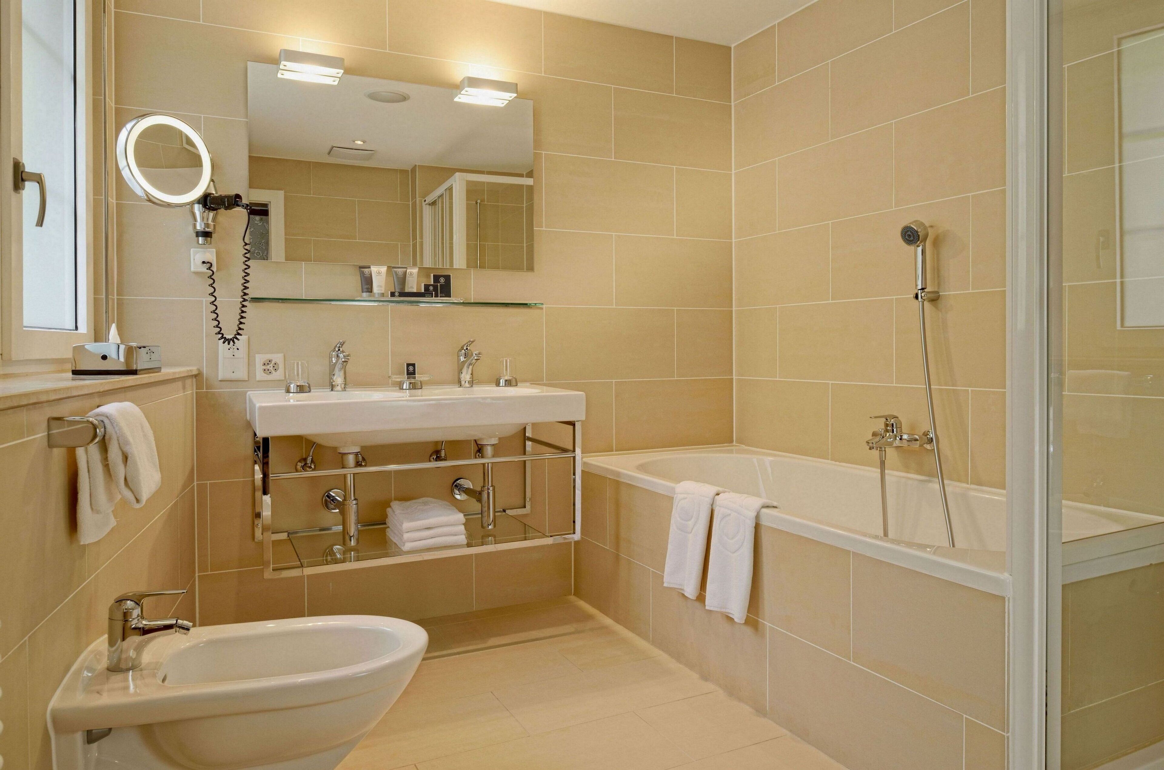 A modern bathroom with a sink, bidet, and bathtub.