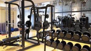 A gym with weightlifting equipment, including a squat rack and dumbbells. - Hotel Monte Rosa (Zermatt)