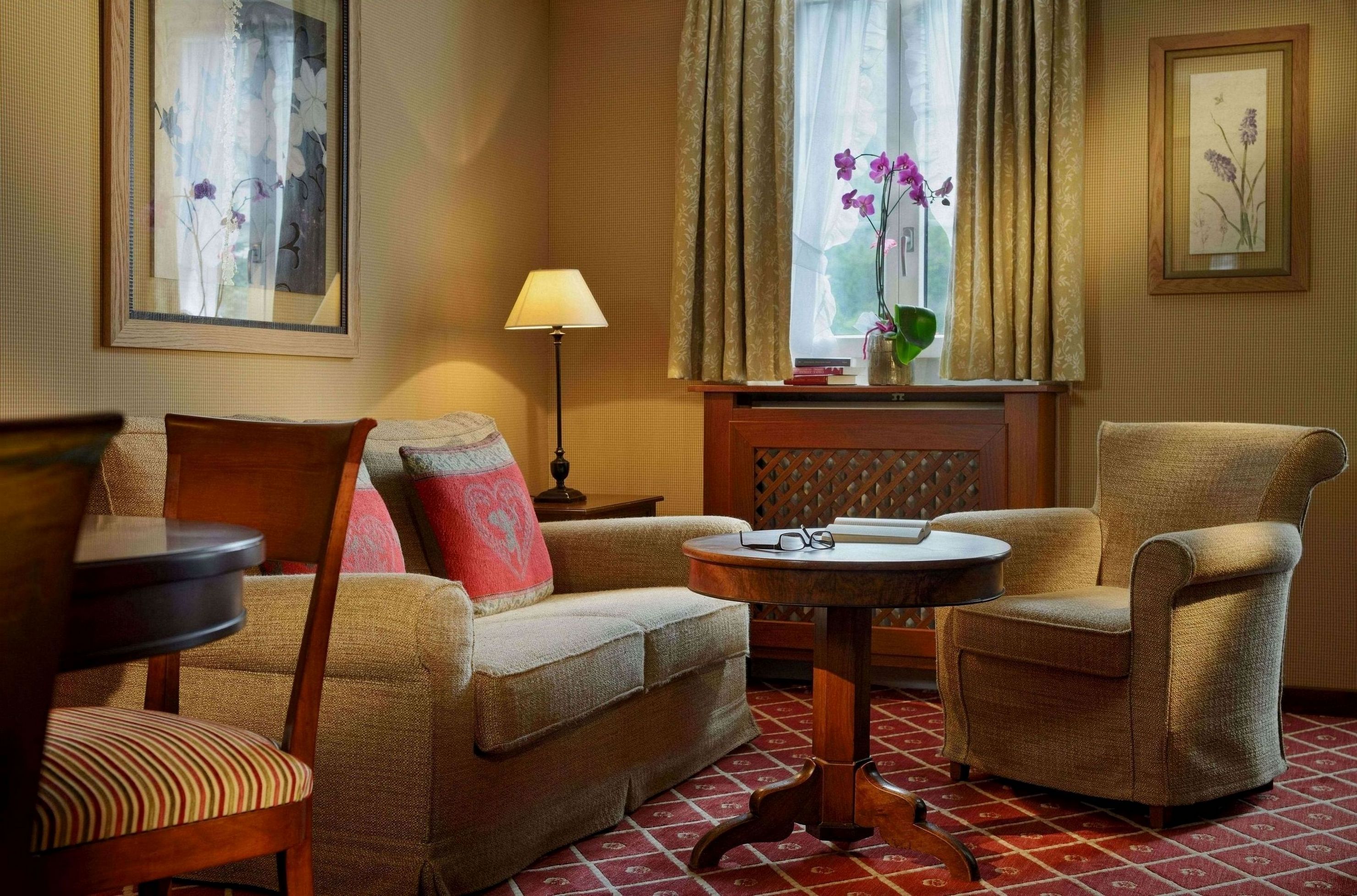 A cozy living room with a sofa, two armchairs, a small round table, and a lamp.