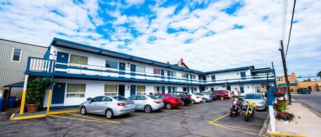 Un motel doté de nombreuses places de stationnement et où une moto est garée à l’extérieur.