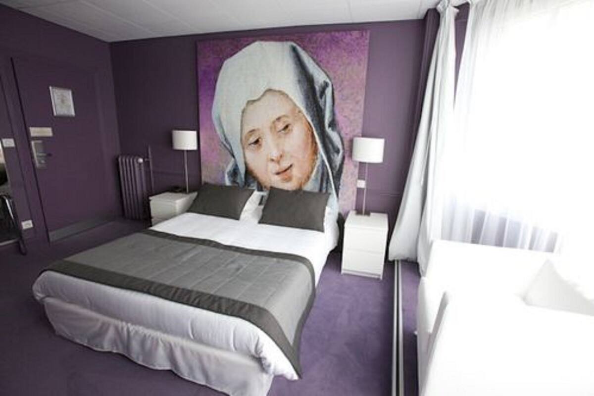 Una habitación de hotel con una cama grande, dos mesitas de noche y una lámpara de pared.