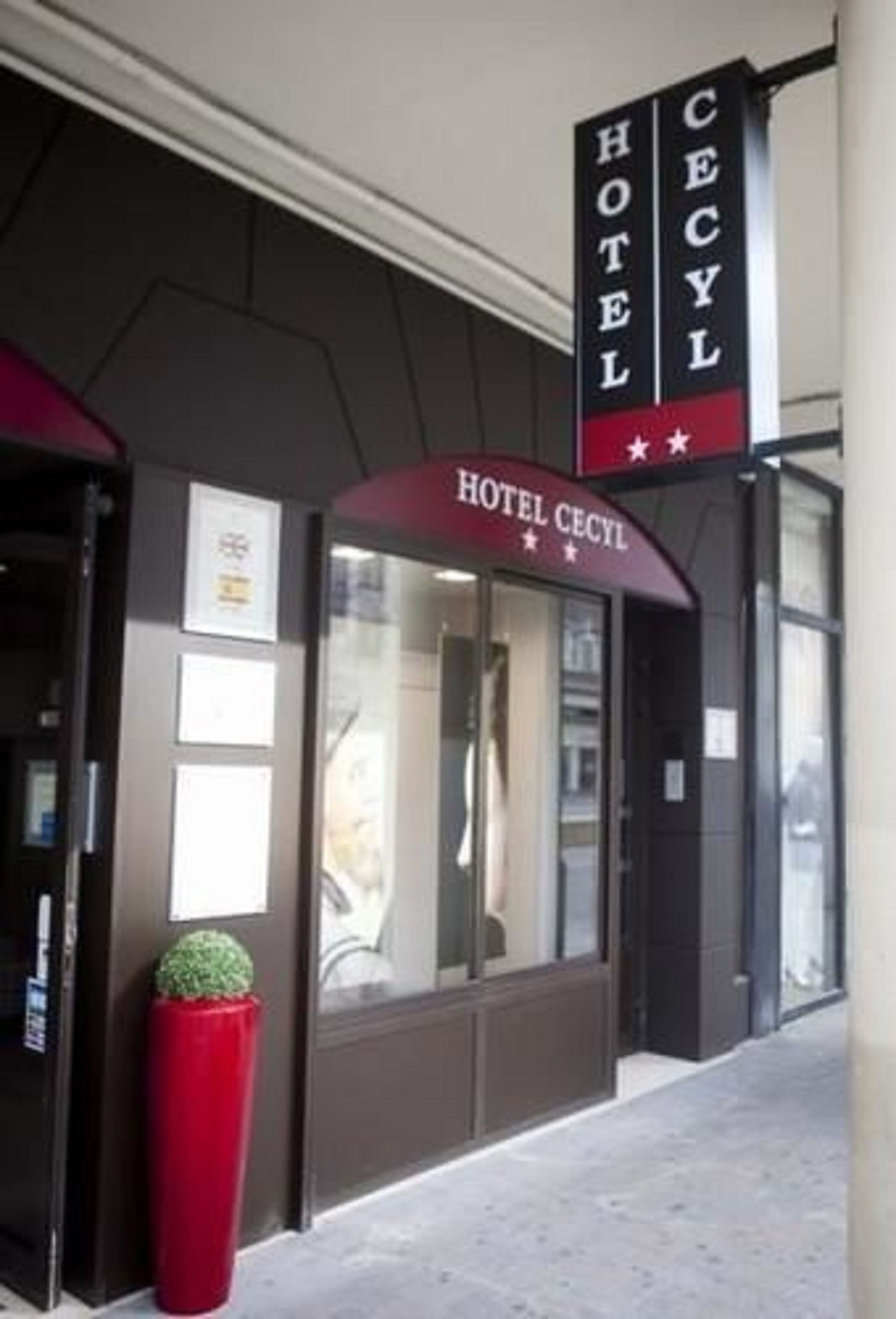 The exterior of Hotel Cecil with a clear entrance and a red planter.