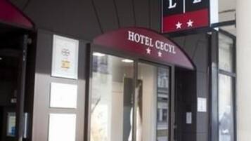 The exterior of Hotel Cecil with a clear entrance and a red planter.