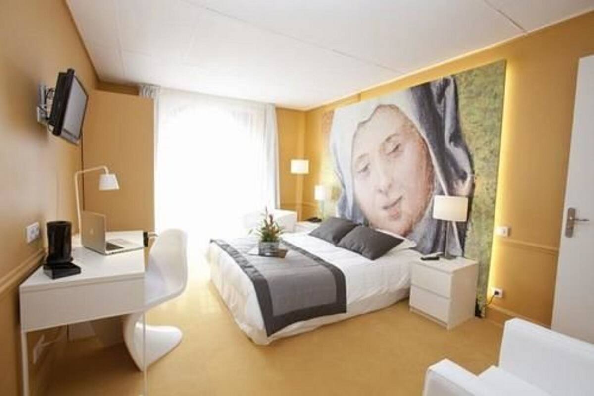 Una habitación de hotel moderna con cama, mesitas de noche, escritorio, silla y televisor.
