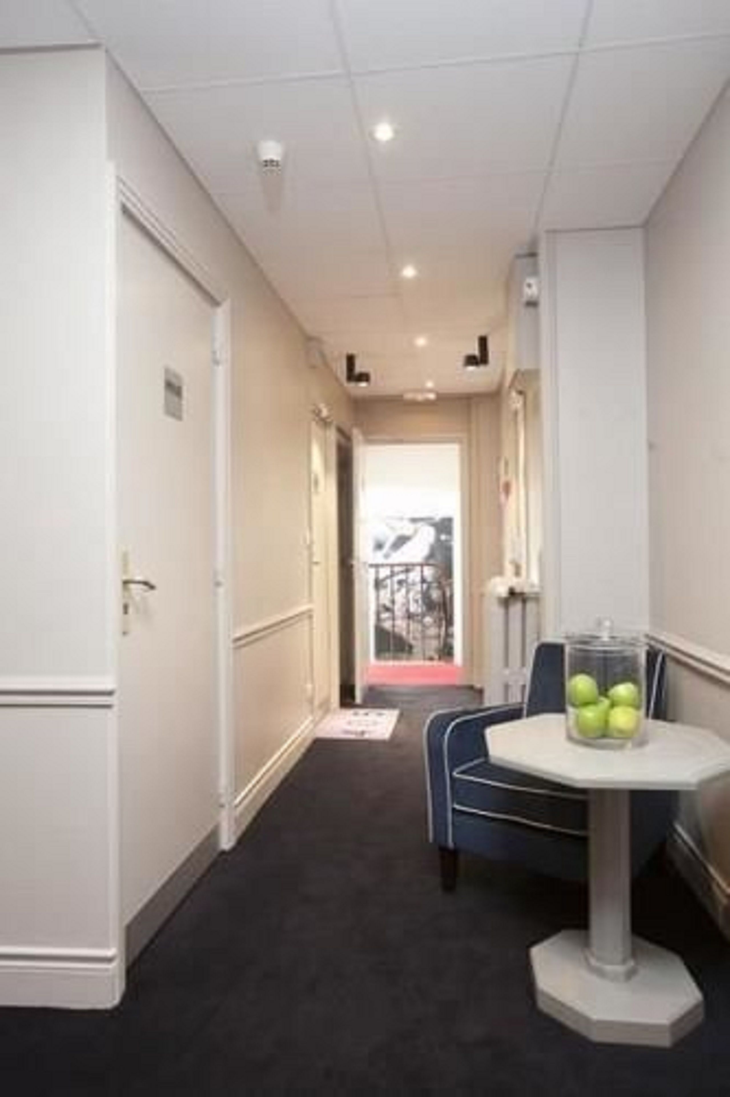 A hotel corridor with a round table and chairs, a door, and a view of the outside.
