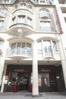 En bygning i klassisk arkitekturstil, med en markant indgang og et skilt, hvor der står "HOTEL CECYL".