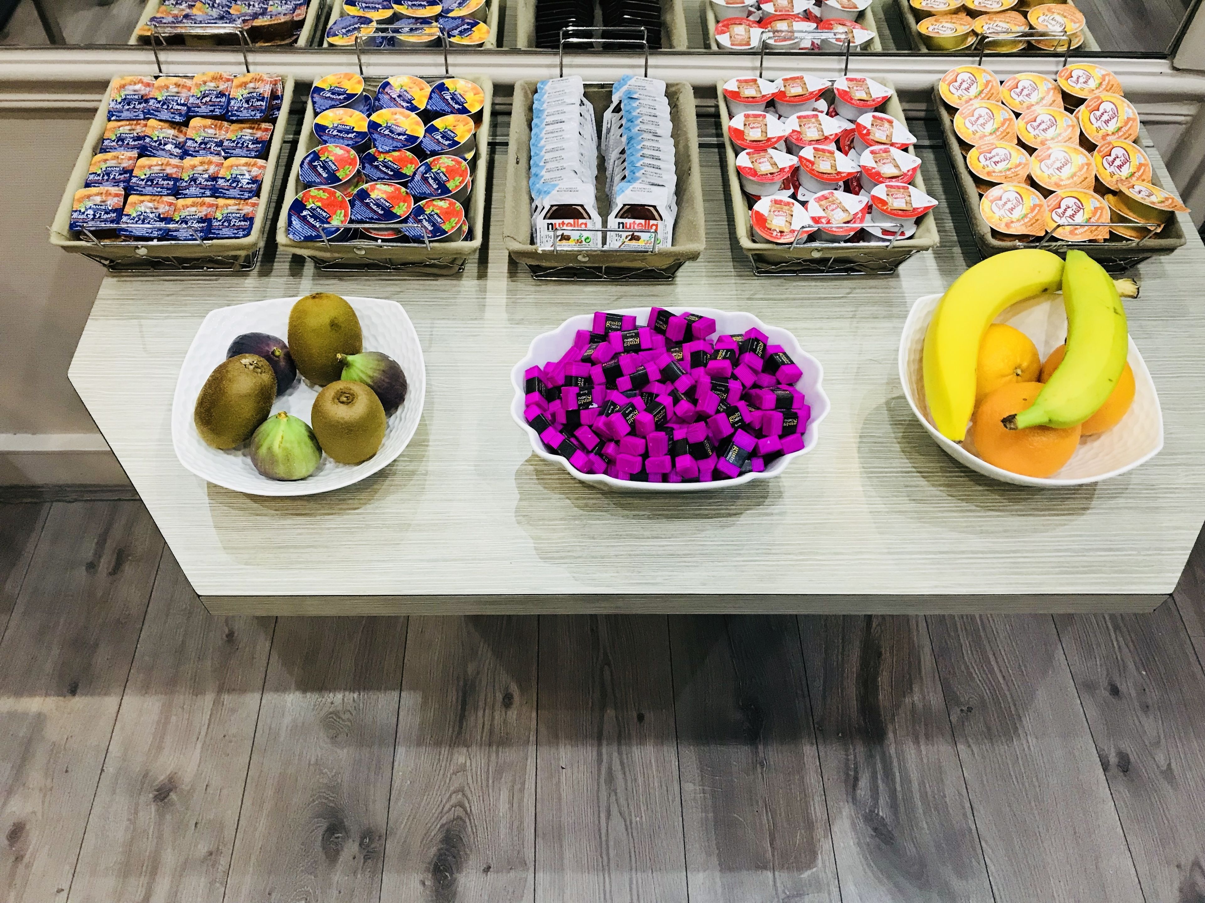 Un buffet con diverse pietanze, tra cui frutta, noci e snack confezionati.