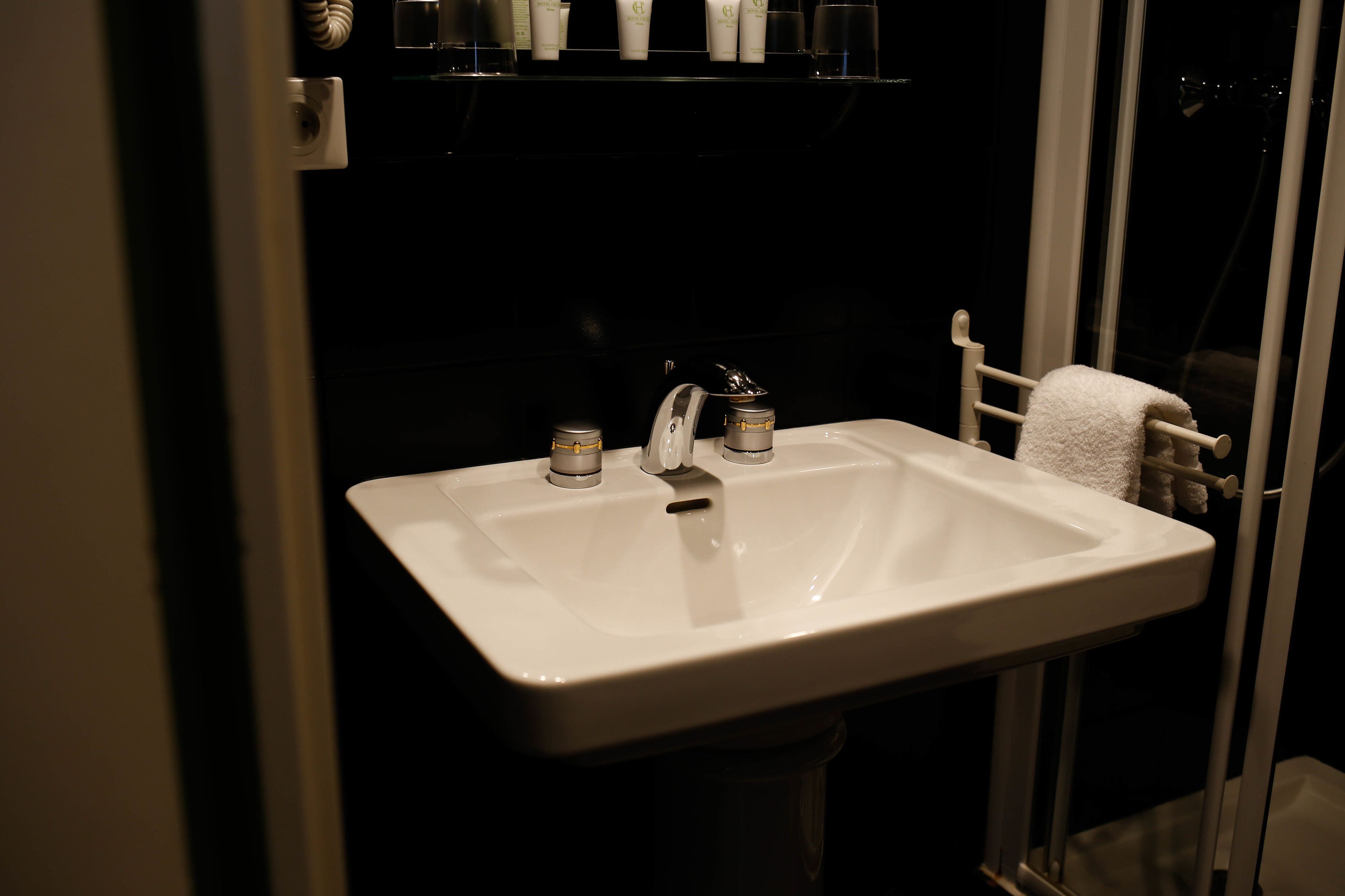 A bathroom with a white sink, a mirror, and a towel rack.