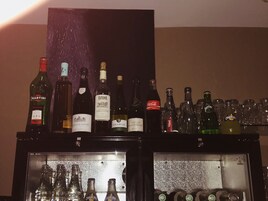Uma área de bar com diversas garrafas de bebidas alcoólicas e copos.