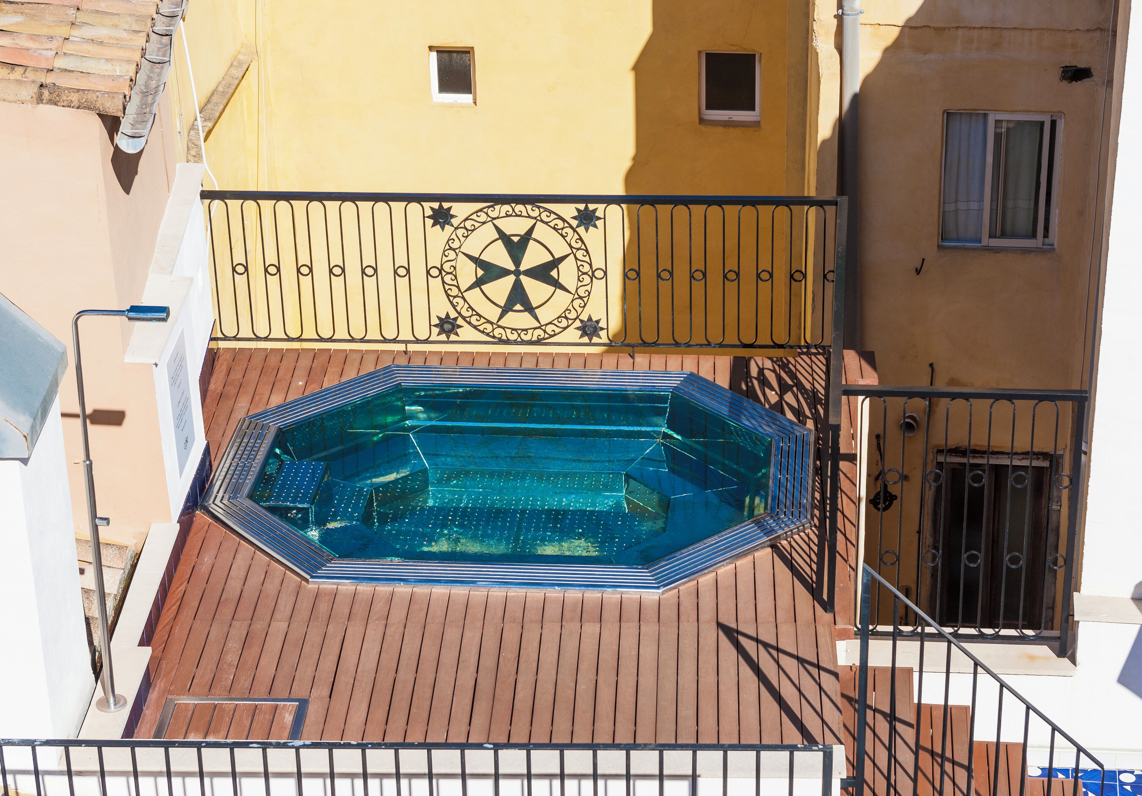 Una piscina gegant a la terrassa del sostre, amb disseny d'estrella, envoltada d'un pont de fusta i baranes metàl·liques.