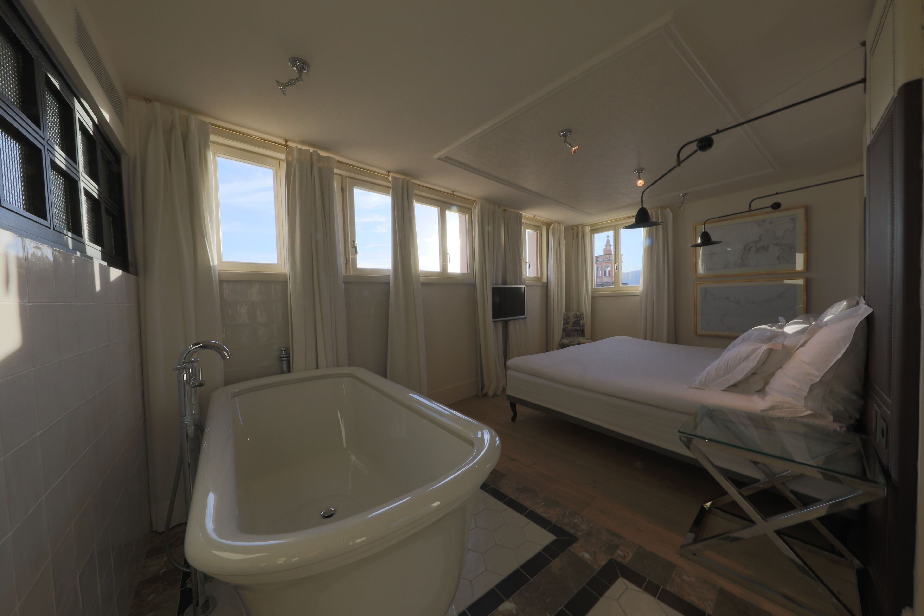 Un baño moderno con una bañera independiente, una cama grande y un televisor.
