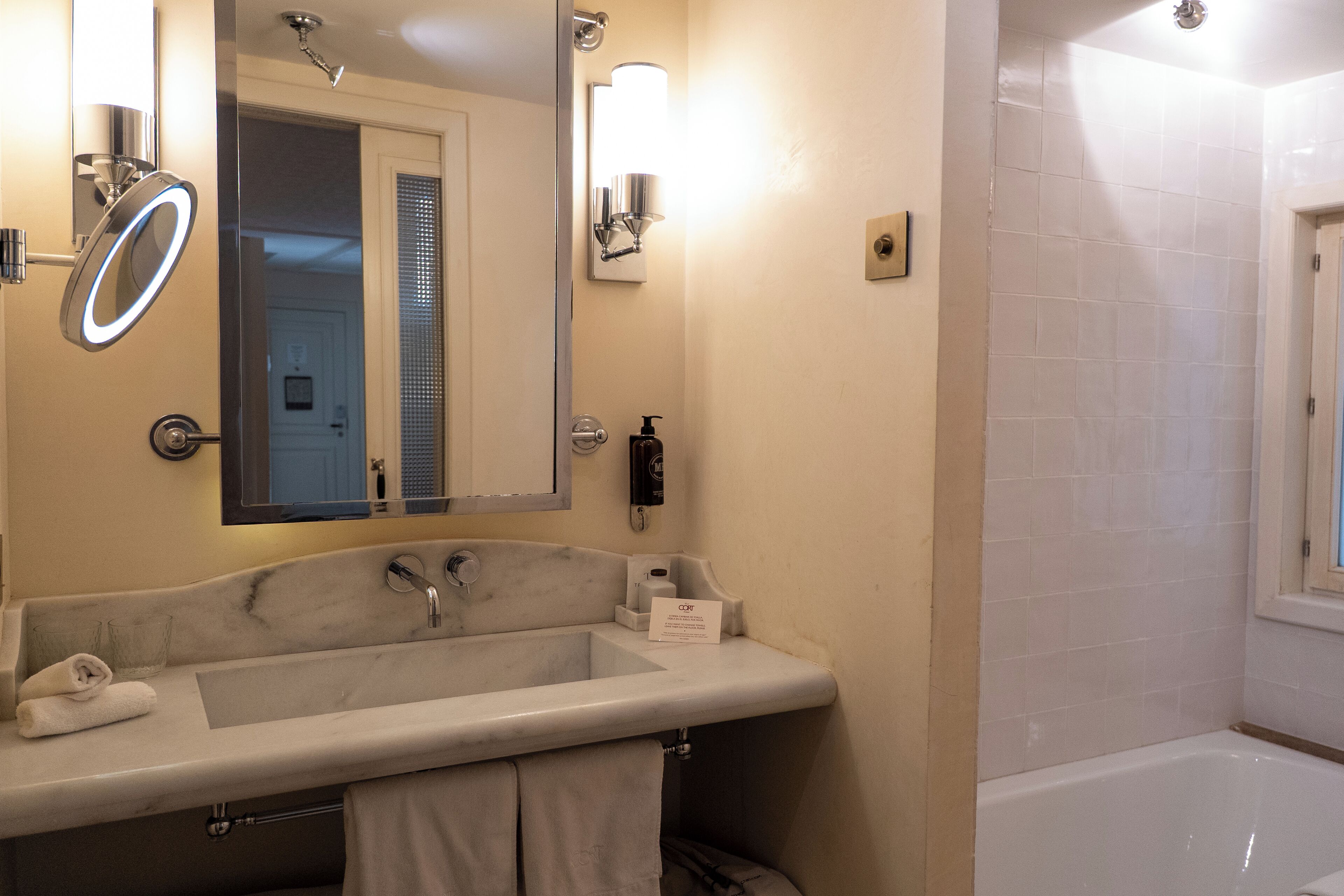A bathroom with a large sink, a mirror, a handheld showerhead, and a bathtub.