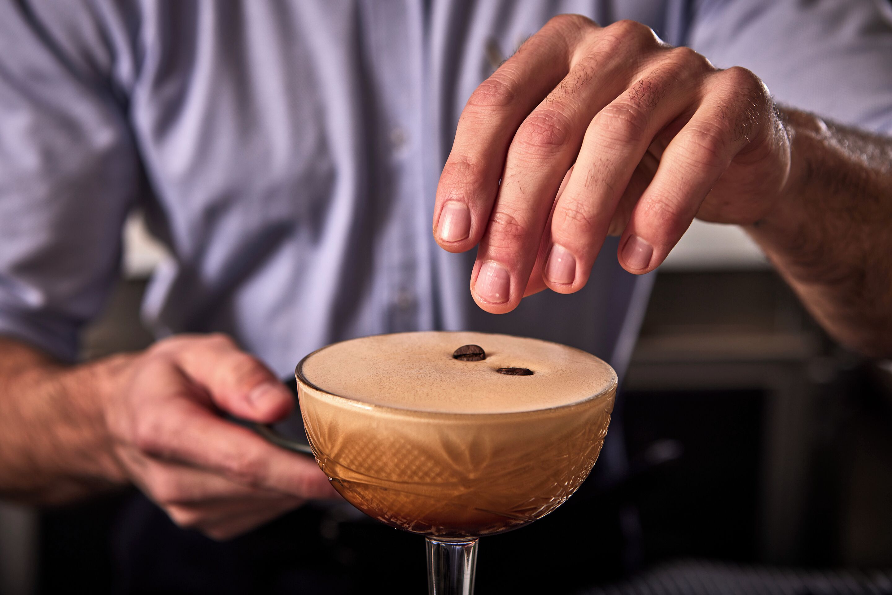 Une personne tenant un verre à martini dont le bord supérieur est givré.