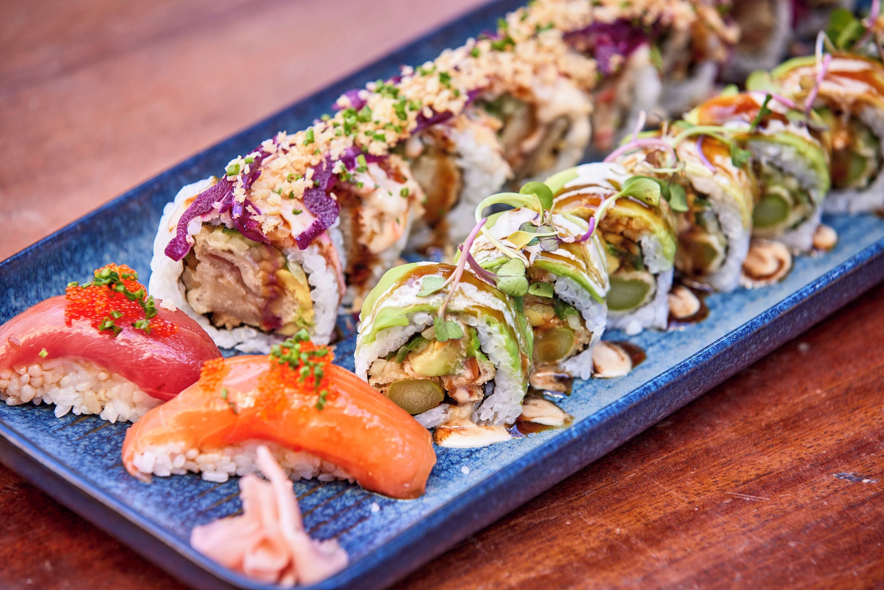 Ett sushi-fat med olika sorters sushi, serverat på en blå tallrik.