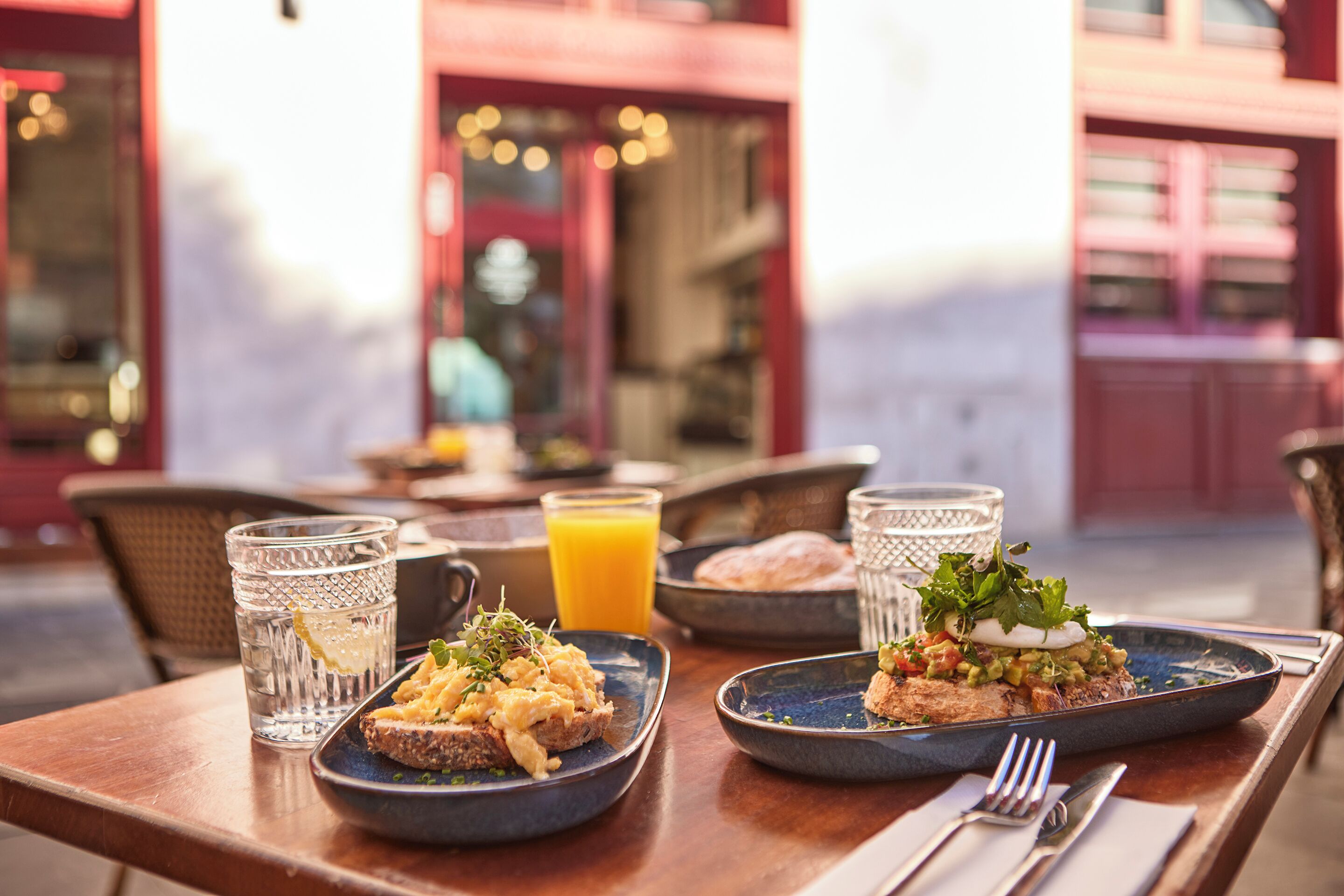 A dining table with breakfast plates, glasses, and a juice pitcher.