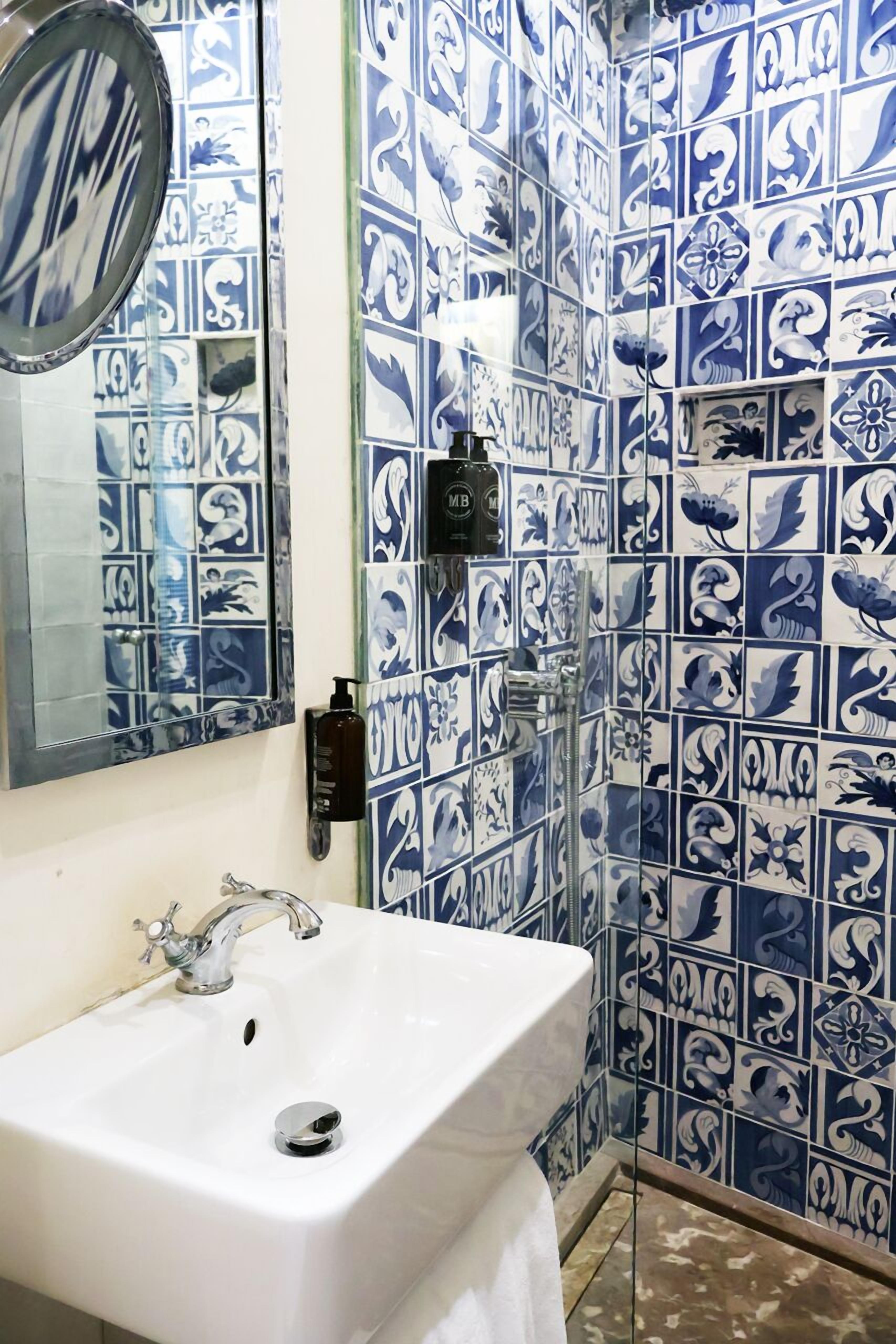Une salle de bain avec un lavabo blanc, un miroir et des carreaux à motifs bleus et blancs.