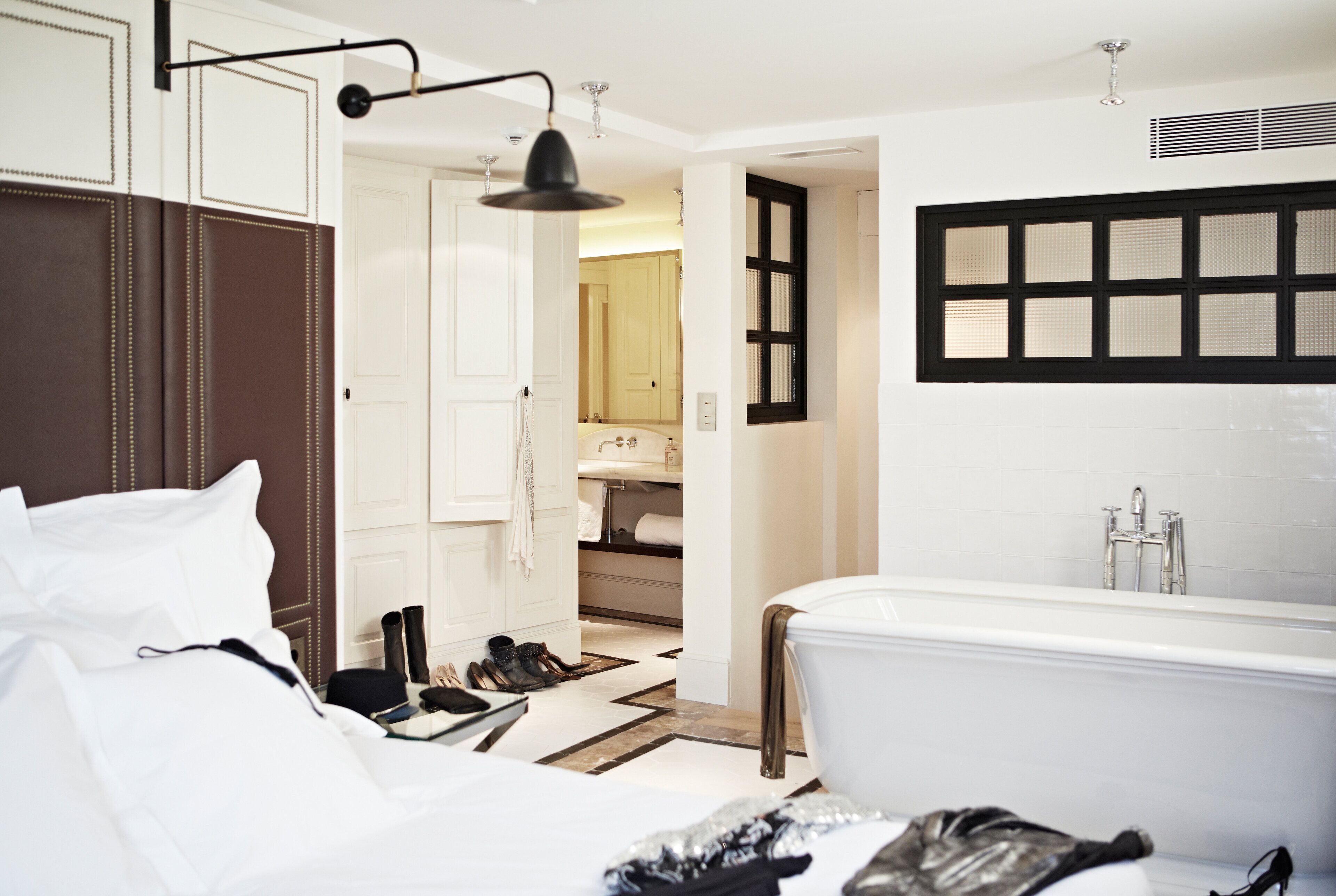 A modern hotel room with a large bed, a separate bathroom with a bathtub, and a walk-in closet.