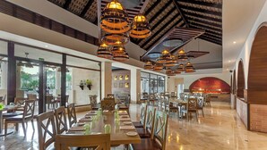 A spacious dining area with long tables, wooden chairs, and hanging pendant lights. - Royalton Splash Punta Cana, An Autograph Collection All-Inclusive Resort & Casino (Punta Cana)