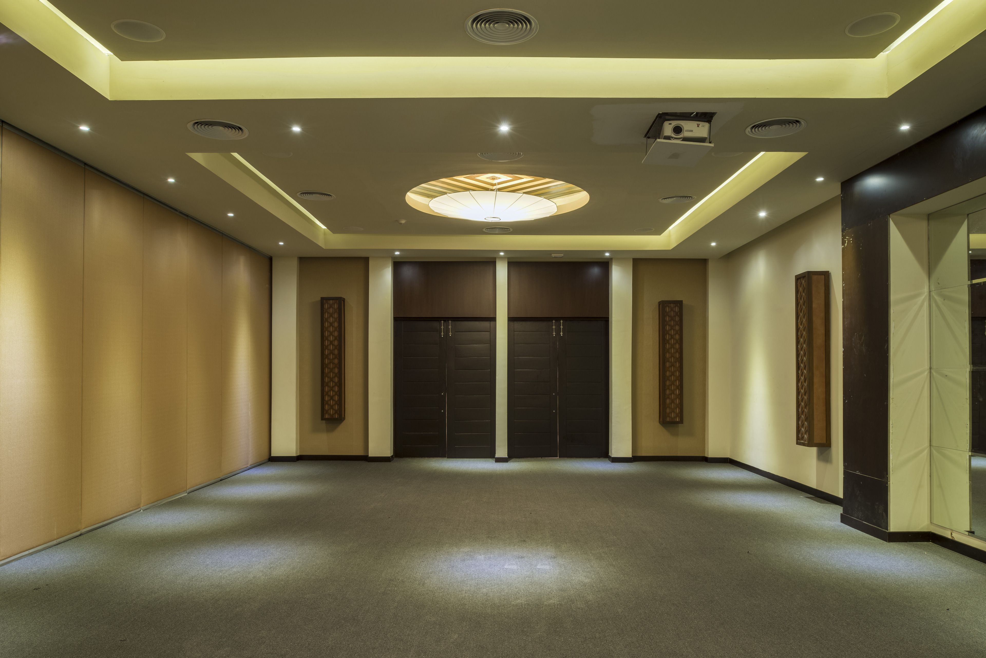 Un'ampia hall con un moderno design del soffitto, illuminazione incassata e un'imponente porta a fondo corridoio.