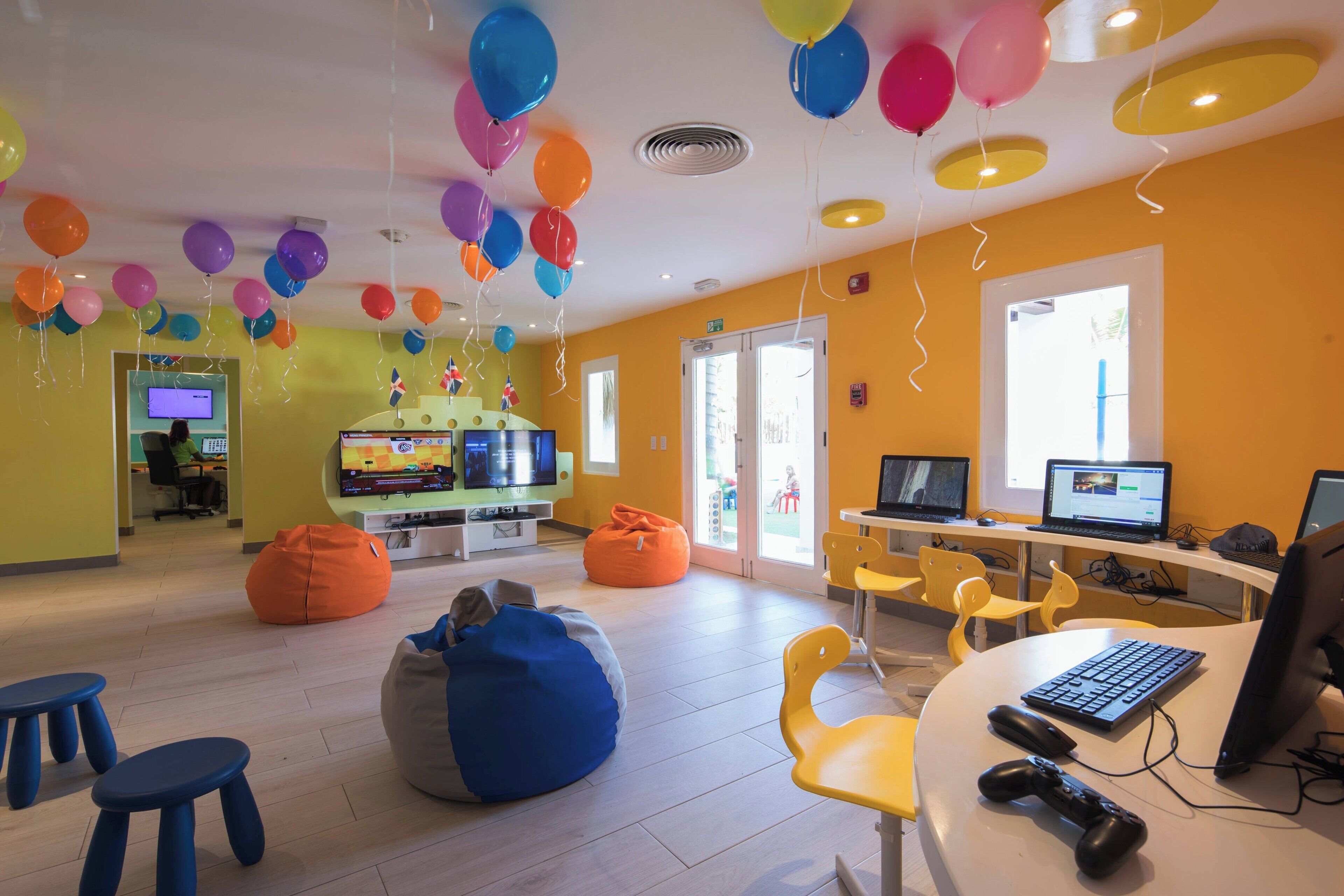 A brightly lit room with yellow walls, a computer desk with a keyboard and mouse, and bean bags.