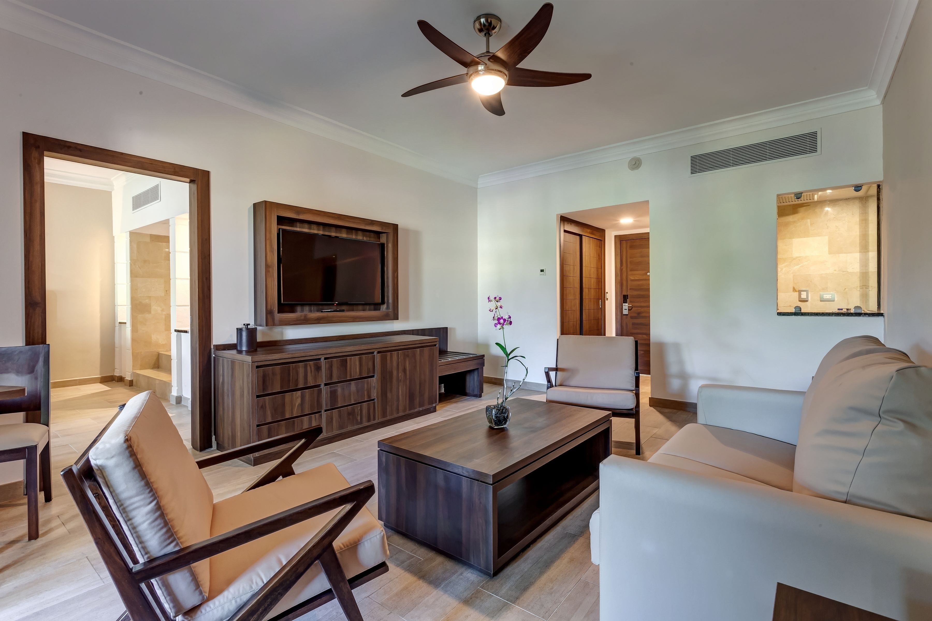Ein modernes Wohnzimmer mit Flachbildfernseher, Holz-Unterhaltungseinheit und Deckenventilator.