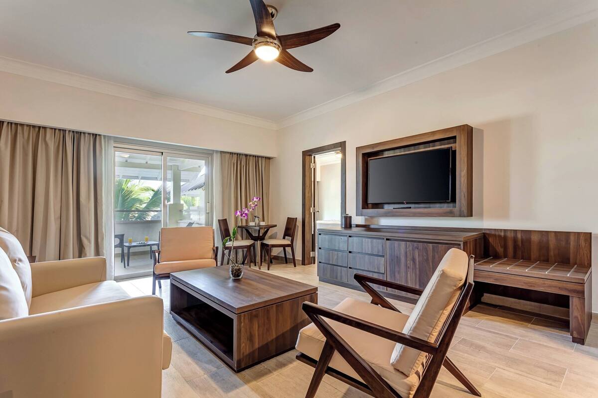 A modern living room with a sofa, coffee table, TV, and a ceiling fan.
