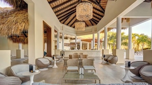 A spacious lounge area with wicker furniture, a central table, and a thatched ceiling. - Royalton Splash Punta Cana, An Autograph Collection All-Inclusive Resort & Casino (Punta Cana)