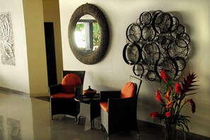 Eine moderne Lobby mit einem runden Spiegel, einem Wandbild und einer Sitzecke mit zwei Stühlen und einem Tisch.